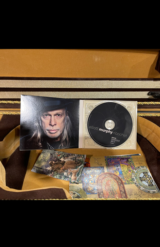 Artistic CD and fold-open CD cover displayed inside an open acoustic guitar.